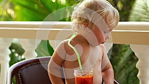 Child boy drinking and playing with a healthy vegetable-fruit smoothie - healthy eating, vegan, vegetarian, organic food