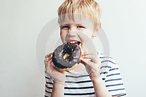 A child boy eats a chocolate donut