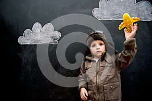 Child, boy and face by blackboard with plane for creative fun, playing or drawing of clouds for imagination. Student