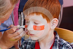 Child boy face painting, making tiger eyes process