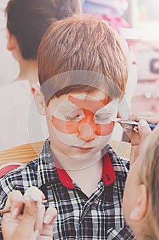 Child boy face painting, making tiger eyes process