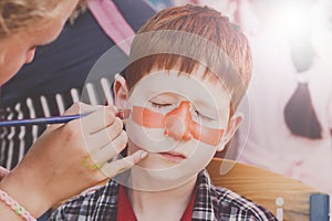 Child boy face painting, making tiger eyes process