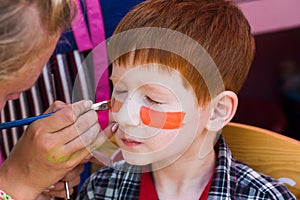 Child boy face painting, making tiger eyes process