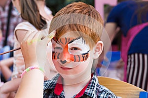 Child boy face painting, making tiger eyes process