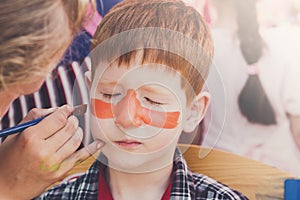 Child boy face painting, making tiger eyes process