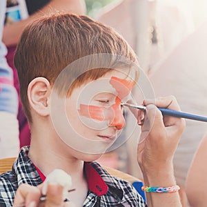 Child boy face painting, making tiger eyes process