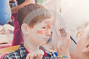 Child boy face painting, making tiger eyes process