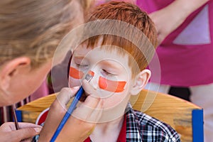 Child boy face painting, making tiger eyes process