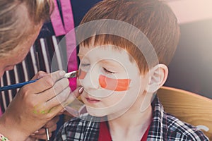 Child boy face painting, making tiger eyes process