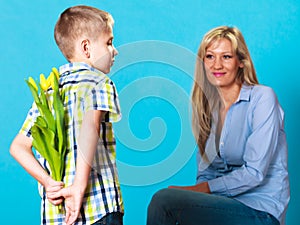 Child boy giving flowers his mother