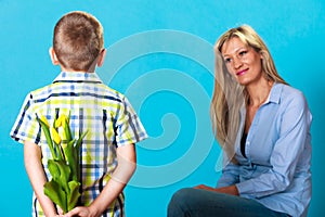 Child boy giving flowers his mother