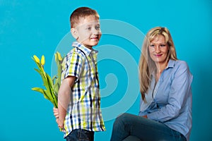 Child boy giving flowers his mother