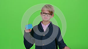 Child boy with glasses looked at credit card and showed dislike on a green screen