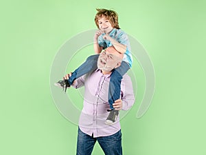 Child boy and grandfather with funny face isolated piggyback ride. Elderly old relative with child.