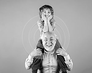Child boy and grandfather piggyback with funny face isolated on blue in studio. Granddad and cute boy with funny face.