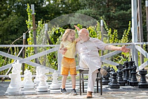 Child boy and grandfather playing chess on big chess board. Spending time together with granddad. Family Relationship