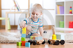 Child boy is happy to play toy building blocks and loader car