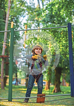 Child boy having fun at adventure park. Happy child climbing in the trees. Cute child boy. Portrait of a beautiful kid