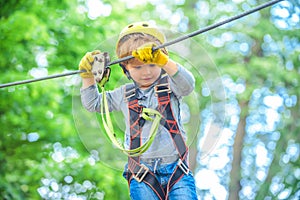 Child boy having fun at adventure park. Happy child climbing in the trees. Happy Little child climbing a tree. Balance