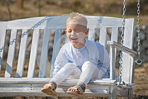 Child boy having fun on a swing. Adorable little kid having fun on a swing outdoor. Spring kids portrait. Kid emotions