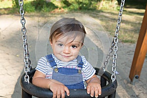 Child boy having fun swinging at garden park