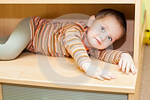 Child boy hiding in cupboard