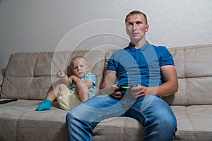 Child boy and his father play with a playstation together