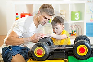 Child boy and his father repair toy car