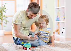 Child boy and his father repair toy car at home