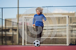 Child boy hold classic soccer ball on playground. Kid holding football ball in studio. Kid playing with ball. Sport