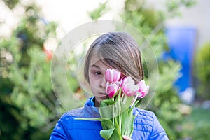 Child, boy holding pink tulips , hiding behind them, mothers day concept