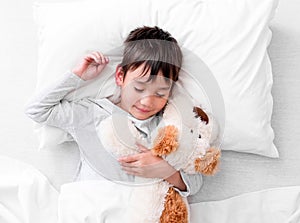 Child boy holding plush toy while sleeping