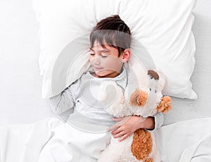 Child boy holding plush toy while sleeping