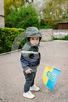 Child boy holding Ukrainian flag, asking for peace, children against war, kids in danger, stop fighting. National symbol of