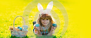 Child boy hunting easter eggs. Wide photo banner for website header design. Kid boy lying on the grass and finding