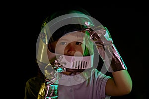 Child boy imagines himself to be an astronaut in an space helmet. Close up kids face on black.