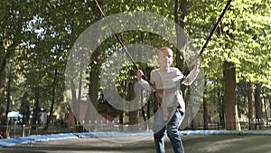 Child boy jumping fastened on a trampoline in summer park.