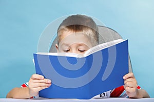 Child boy kid reading a book on blue