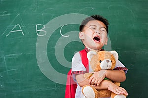 Child boy from kindergarten in student uniform with school bag smiling and hugging teddy bear