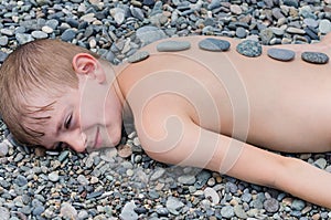 Child boy laying on the pebbles. Massage stones, rest and relaxation