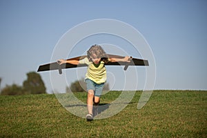 Child boy like a pilot with toy wings against blue sky. Kids freedom concept. Dreams of becoming a pilot. Kid pilot with