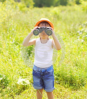 Child boy looks in binoculars outdoors in summer