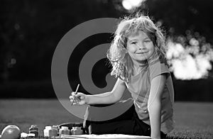 Child boy painting in spring nature. Schooler kids drawing in summer park, painting art. Little painter draw pictures photo