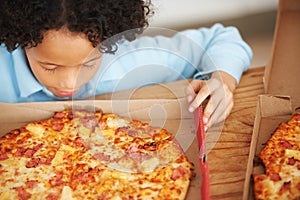 Child, boy and pizza takeaway box for hungry snack, junk fast food dinner at kitchen table. Male person, kid and