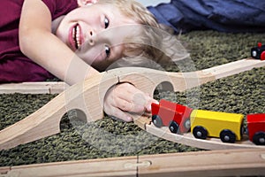 Child boy play with wooden train, build toy railroad at home or