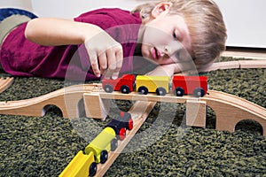Child boy play with wooden train, build toy railroad at home or