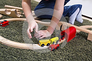 Child boy play with wooden train, build toy railroad at home or