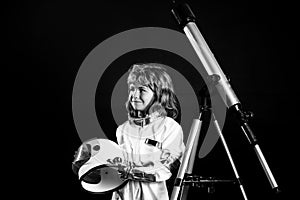 Child boy playing astronaut spaceman with telescope on black. Success, creative and start up concept.