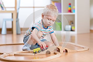 Child boy playing in his room with a toy train