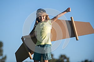 Child boy playing with plane wings outdoors. Cute boy playing pilot and dreaming of becoming a spaceman aviator pilot